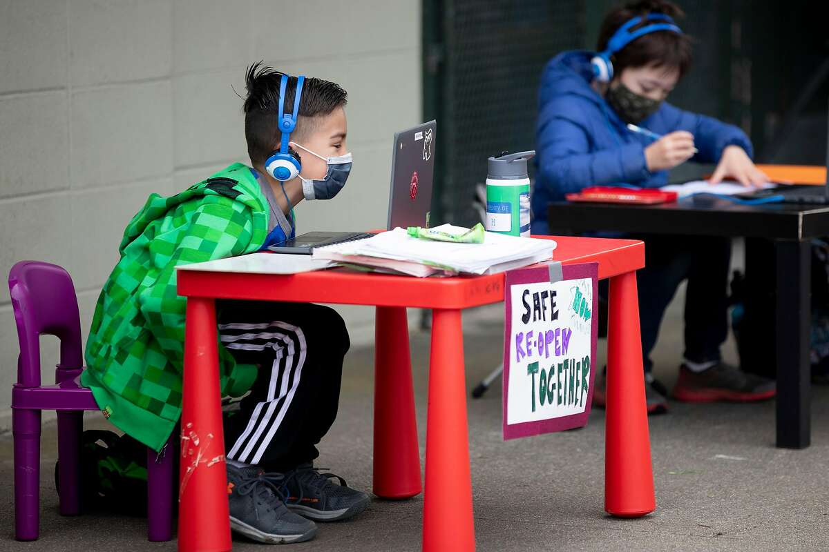 H. Suchovsky, 8, (left) and Evan Carnicelli, 7, sit side by side while attending class on their computer alongside fellow students at Midtown Terrace Park across the street from Clarendon Elementary School in San Francisco, Calif. Thursday, February 18, 2021 to participate in a “Zoom in” demonstration with fellow students attending classes outside their schools to bring attention to reopening.