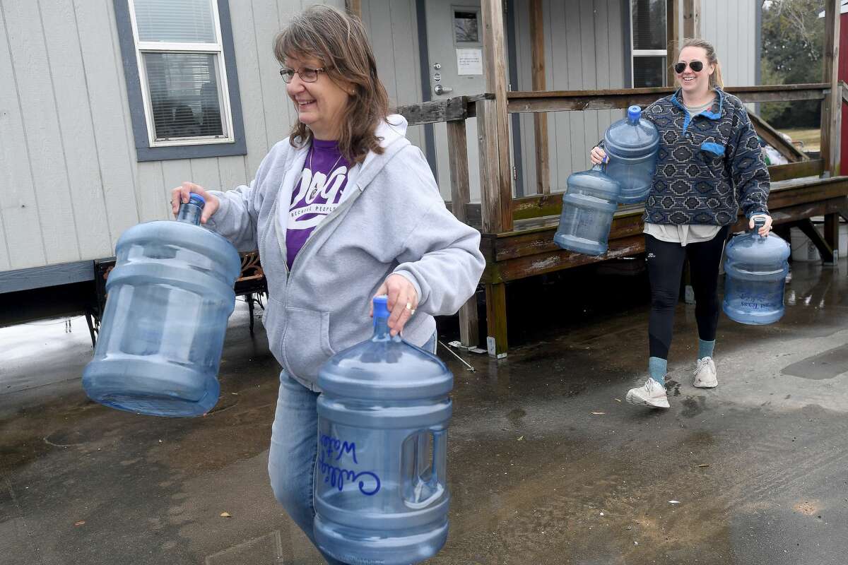 Shelter Manager Dee Dee Goode (left) helps Monica Lee carry empty jugs to her car at the Humane Society of Southeast Texas, which has been without water since Monday. The shelter has been reaching out through social media for donations to help provide drinking water for the animals, as well as water to clean. Lee, a former employee who continues helping whenever needed, has a well system of purified water and has been drawing from it to help amid the water crisis. Photo made Thursday, February 18, 2021 Kim Brent/The Enterprise