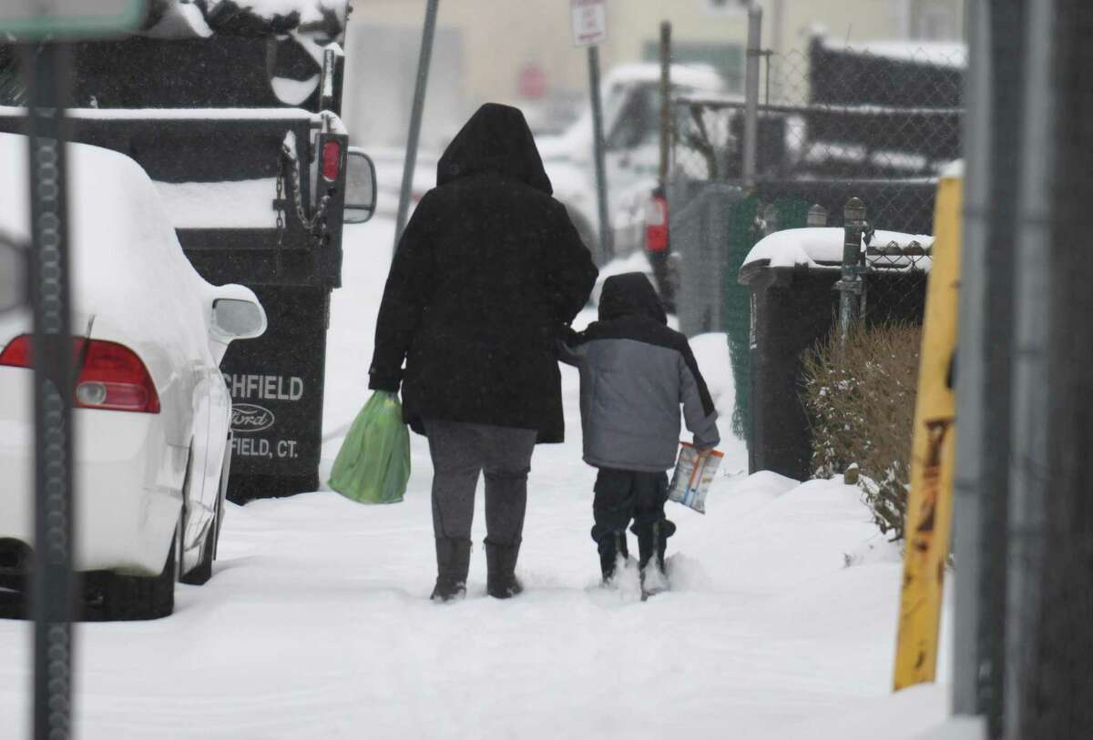 A mother and child walk in the snow in the South End of Stamford, Conn., on Thursday, Feb. 18, 2021.