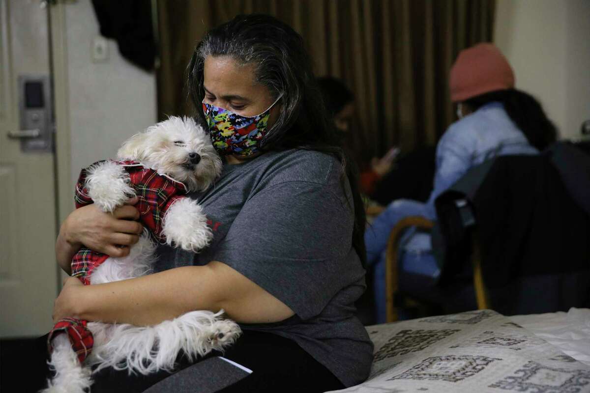 Ginette Palmer cuddles her family pet, Major, as her husband, Eddie, undergoes peritoneal dialysis at a motel on Wednesday, Feb. 18, 2021.