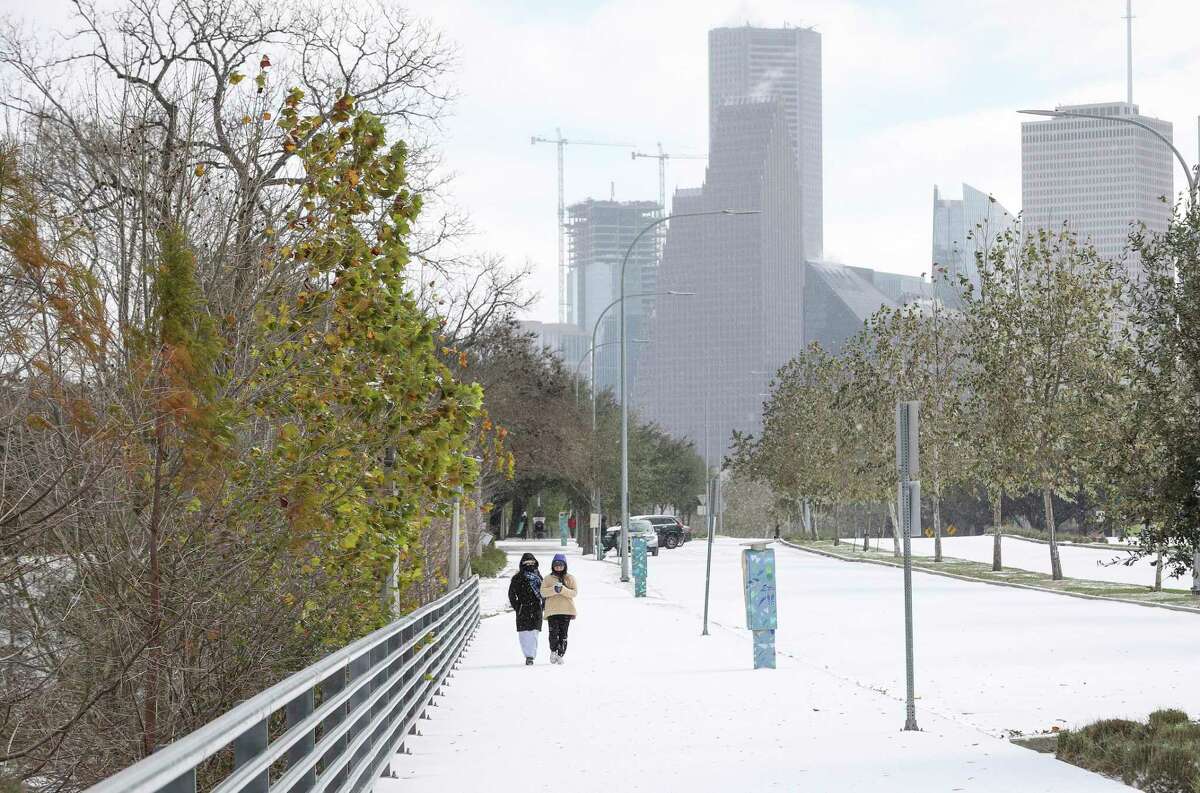 Two women walk along Allen Parkway as a winter storm hits Houston on Monday, Feb. 15, 2021, at Buffalo Bayou Park in Houston.