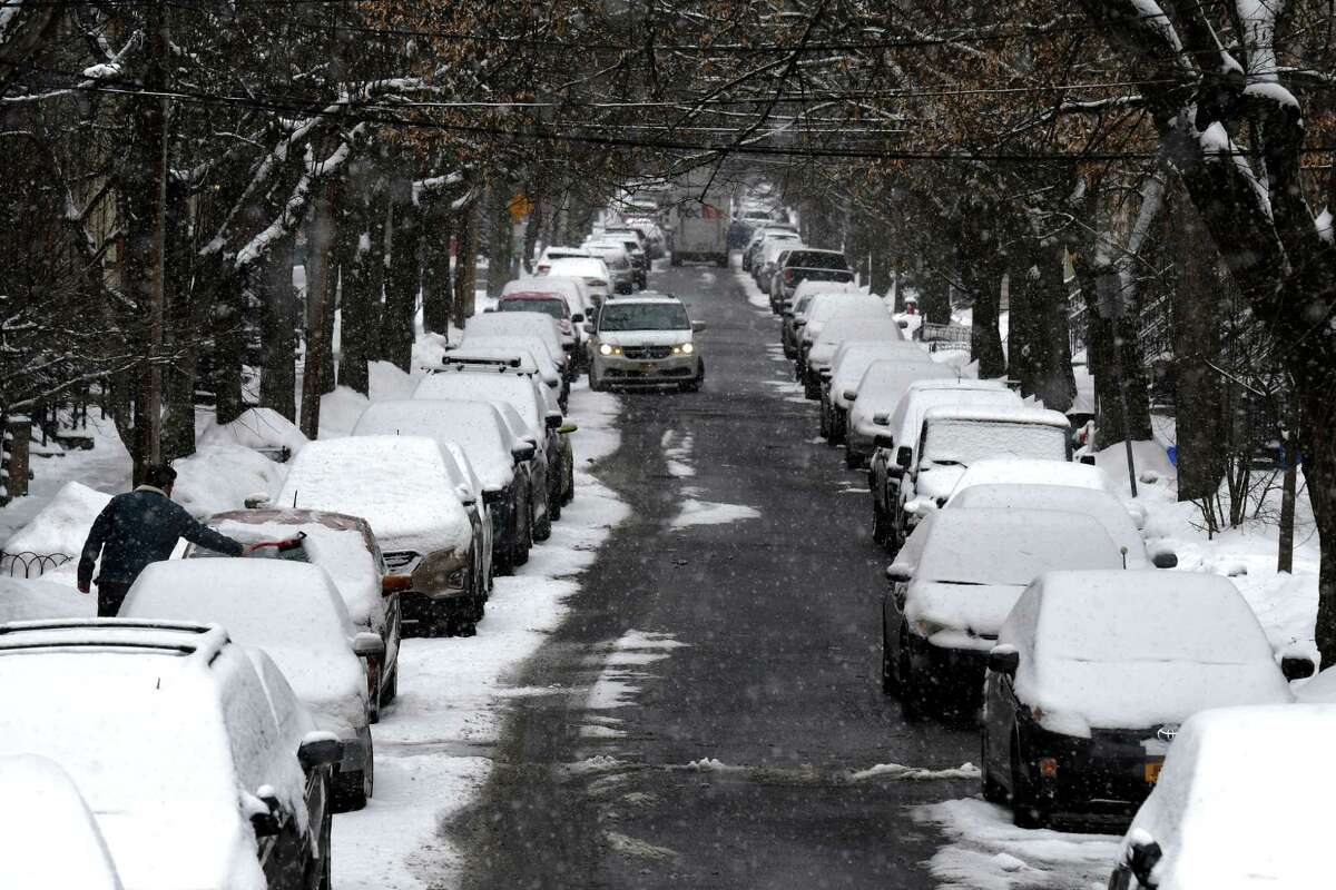 Overnight snow is dusted from a car on Lancaster Street as a day of light snow showers lingered in the Capital Region on Friday, Feb. 19, 2021, in Albany, N.Y. A Getting There reader asks - what is the best way to get a stuck car out of snow? (Will Waldron/Times Union)