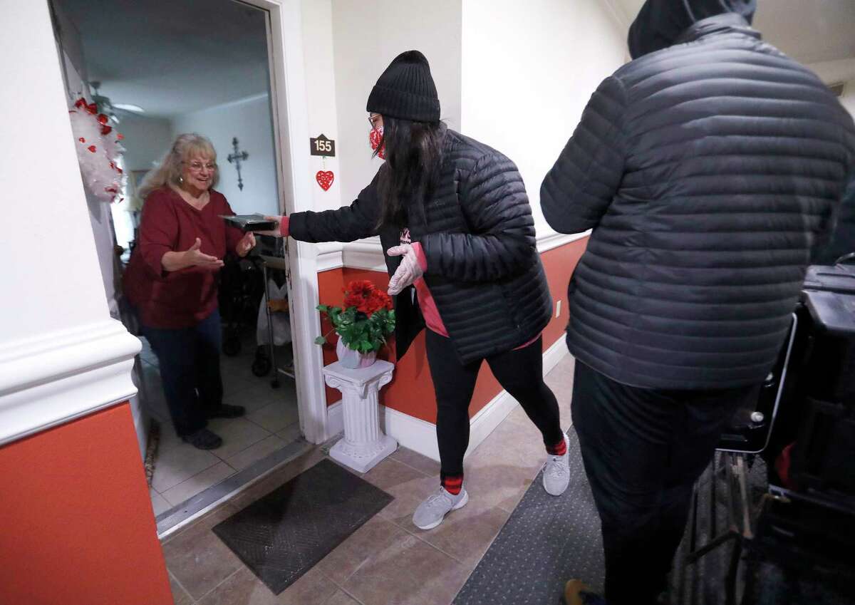 A woman with the Houston Food bank delivers a meal to Gloria Partida, a resident of Big Bass Resort at the Houston Food Bank, in Houston, Thursday, February 18, 2021, after a winter storm left people without power and water along with freezing temperatures.