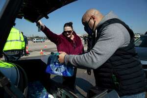 Steven Alexander, of Houston Municipal Courts, puts cases of free bottled water into Kimberly Caldwell's trunk at a mass distribution Friday, Feb. 19, 2021, at Delmar Stadium in Houston. Caldwell said she was very grateful for the distribution. The city is still under boil water order and some places are still having low water pressure.