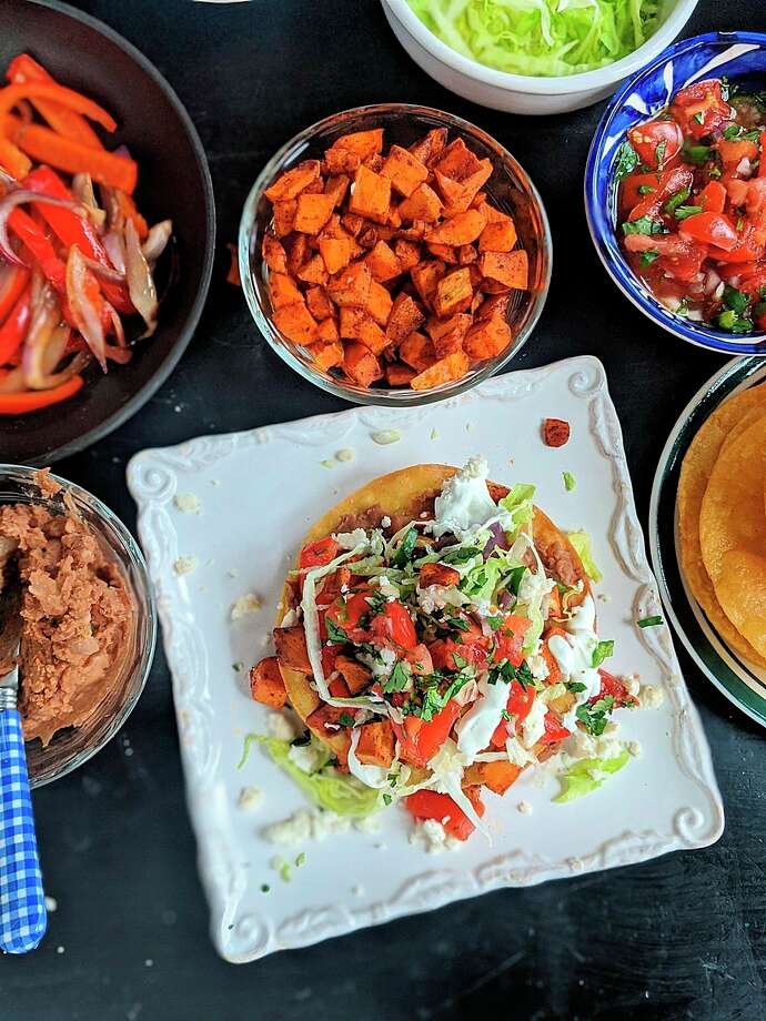 These vegetarian tostadas are stacked with two layers of smashed pinto beans, lettuce, pico and roasted sweet potatoes and bell peppers. Crumbled queso fresco and lime crema add the crowning touch. (Gretchen McKay/TNS) / Pittsburgh Post-Gazette