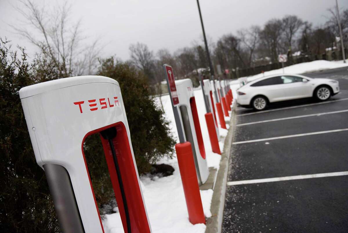 A Tesla electric vehicle charges at one of the high-speed charging ports at the I-95 southbound service plaza in Darien, Conn., on Feb. 9, 2021. Connecticut is looking to expand access to electric vehicles such as Tesla models by improving its EV subsidies program.