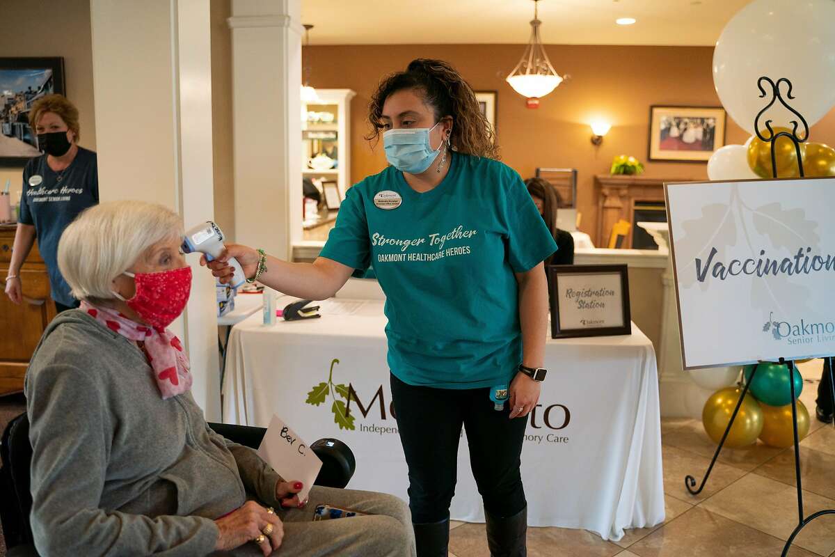 Bev Cullen, 80, left, has her temperature checked by staff member Melinda Alvarez at the Oakmont of Montecito assisted living facility in Concord on Feb. 3.