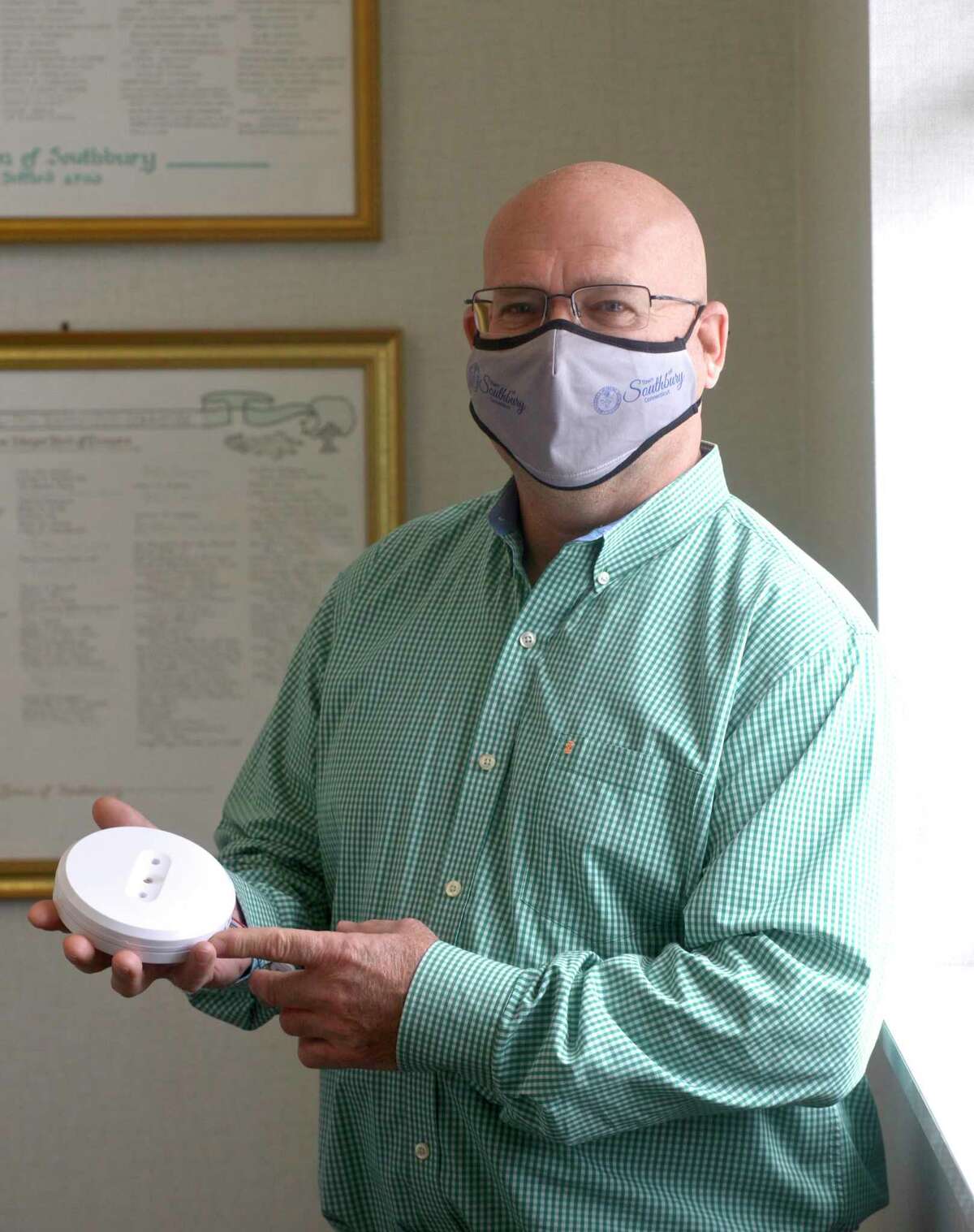 Southbury First Selectman Jeff Manville holds a ultraviolet light-emitting device like the ones installed in Southbury Town Hall at the entranceways to the building and restrooms. The units emit ultraviolet C light to destroy airborne germs, including the coronavirus. Friday, February 19, 2021, in Southbury, Conn.