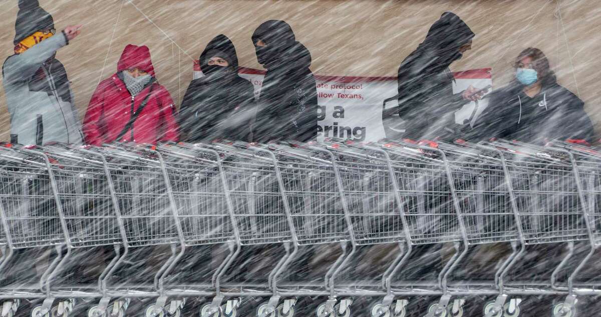People wait in line to enter the H-E-B at West Avenue and Blanco Road as a brisk snow falls Thursday morning.