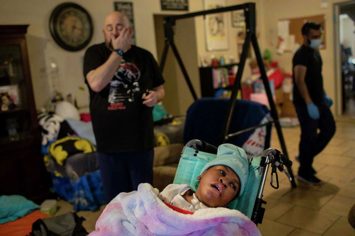Hailey Cheevers, 10, sits in a chair in her living room as her father Stan, left, and Samir Haq, a home-health nurse, prepare the home following several days of winter storms Friday, Feb. 19, 2021, in Houston. Pipes broke in the cold weather causing parts of the ceilings to collapse.