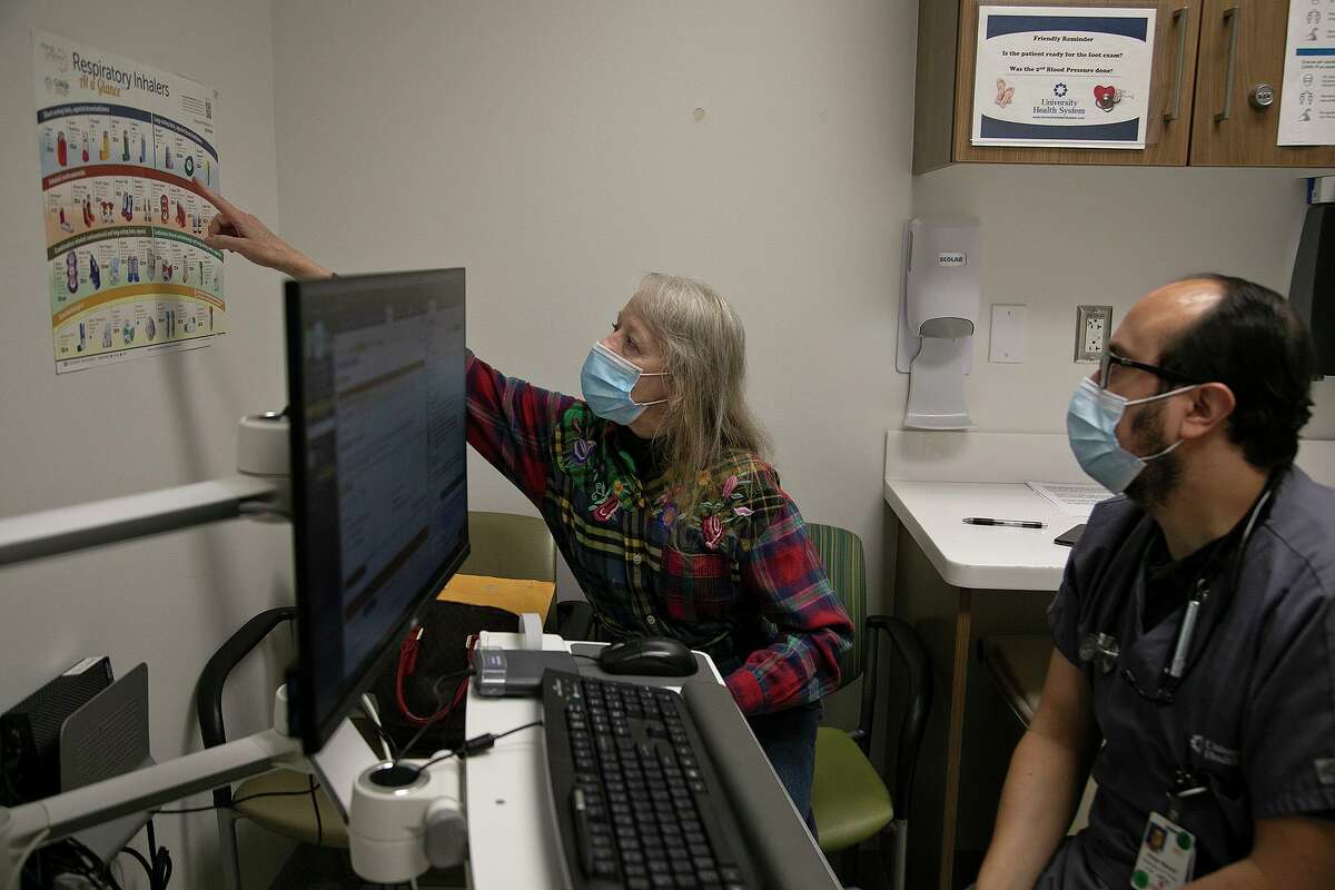 UT Health pulmonologist Dr. Diego Maselli watches as asthma patient Diane Hearn points out the inhaler she has on a poster at University Health's Robert B. Green Campus in San Antonio on Feb. 12, 2021.