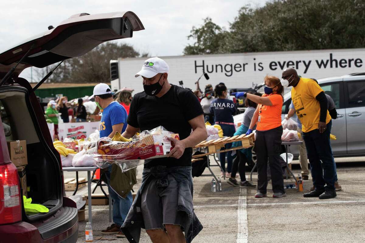 Houston Food Bank employee Enrique Albi, 50, approaches a vehicle to load food during a food distribution event in the aftermath of a freeze that left the Houston area depleted of resources, Sunday, Feb. 21, 2021, in Houston.