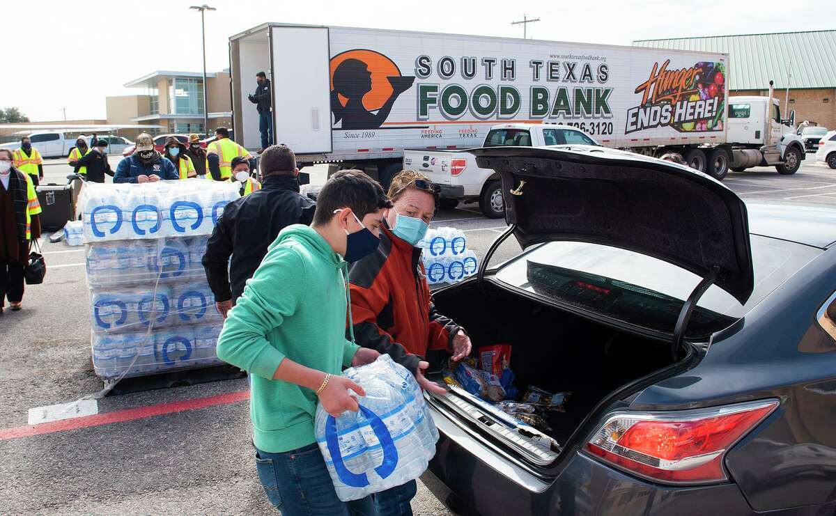 City of Laredo workers and volunteers help load cases of water, loaves of bread and packs of snacks into cars on Tuesday, Feb. 16, 2021, as Laredoans without water or electricity pick up the essentials distributed by the South Texas Food Bank in partnership with the City of Laredo at Nixon High School.
