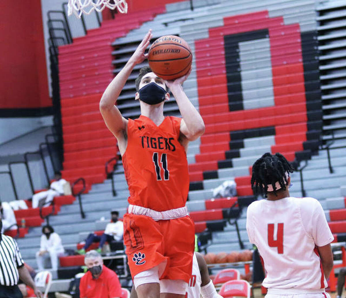 Edwardsville’s Brennan Weller (11) sidesteps Alton’s Lathan O’Quinn and scores two of his 30 points in Saturday’s SWC win over the Redbirds at Alton High in Godfrey. Weller joined the Tigers’ 1,000-points club with his 14th point in the game.