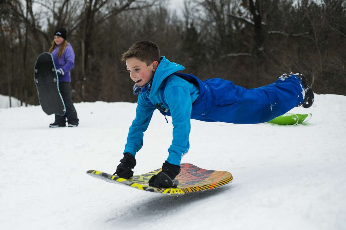 FILE PHOTO: Reid Dryer, 9, jumps onto his sled at the top of the sledding hill at City Forest Monday afternoon, Feb. 22, 2021 in Midland. Midland Public Schools and several other local school districts closed on Monday due to inclement weather. (Katy Kildee/kkildee@mdn.net)