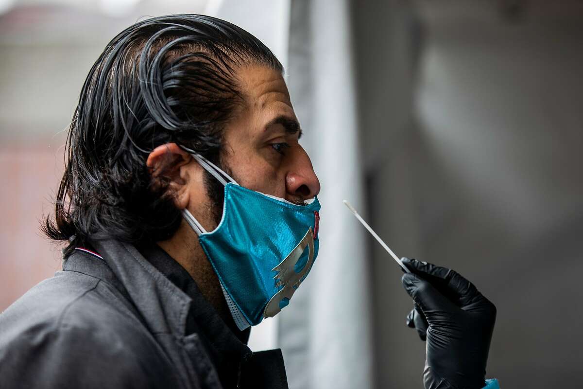Cesar Gomez stands as he prepares to receive an Abbott BinaxNOW COVID-19 test at a rapid testing site at 24th St Mission BART Plaza in San Francisco, California Sunday, Feb. 14, 2021. Gomez, who volunteers at the nearby Mission Food Hub along with fiancée Venecia Margarita, went to be tested together on Valentine's Day.