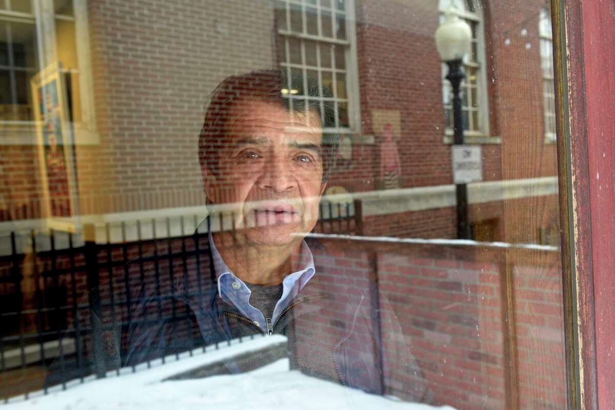 Wilson Hernandez, owner of La Mitad del Mundo restaurant looks through a dining room window. Monday, February 22, 2021, in Danbury, Conn.