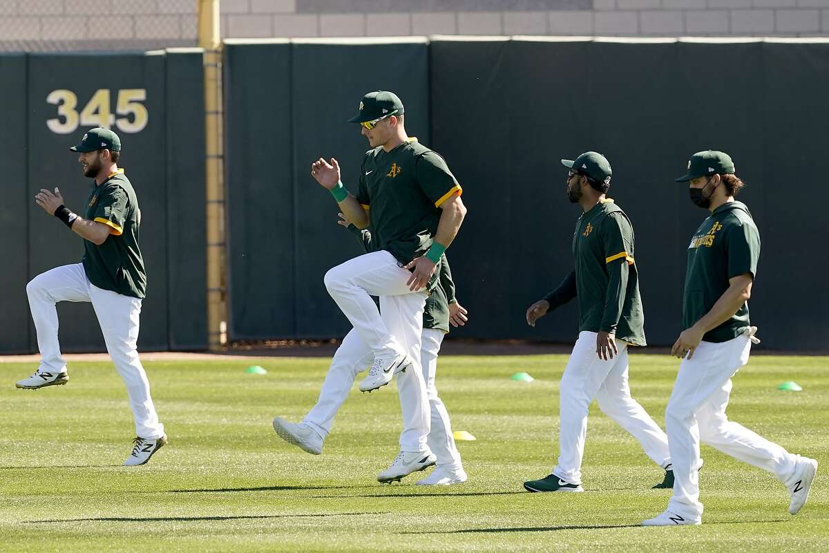 Matt Chapman, center and other Oakland Athletics players warm up during a spring training baseball practice, Monday, Feb. 22, 2021, in Mesa, Ariz. Chapman told sportswriters that at the beginning of spring training 2021 he is feeling good and ready to play following offseason hip surgery.