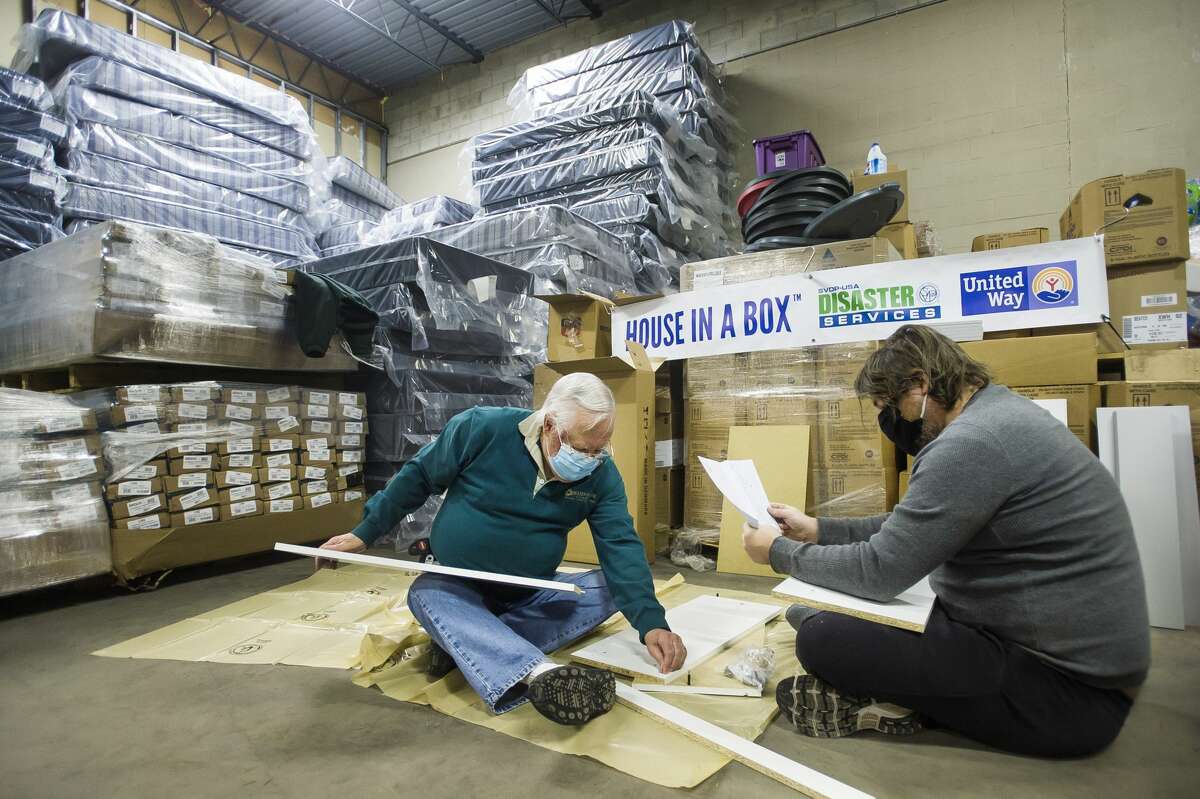 Volunteers Colin Buell, left, and Parker Buell, right, begin assembling one of 50 "House in a Box" kits containing brand new household necessities (couch, bed linens, dinette, dishes, etc.) to distribute to flood survivors Tuesday, Feb. 23, 2021 at the United Way of Midland County warehouse. The project is a collaborative effort between Long Term Disaster Recovery/United Way of Midland County and the Disaster Services Corporation of the Society of St. Vincent de Paul. (Katy Kildee/kkildee@mdn.net)