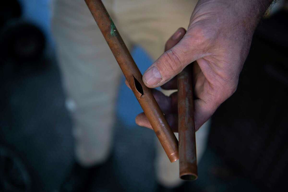 Troy Watts holds a pipe that split as water froze amid plunging temperatures.