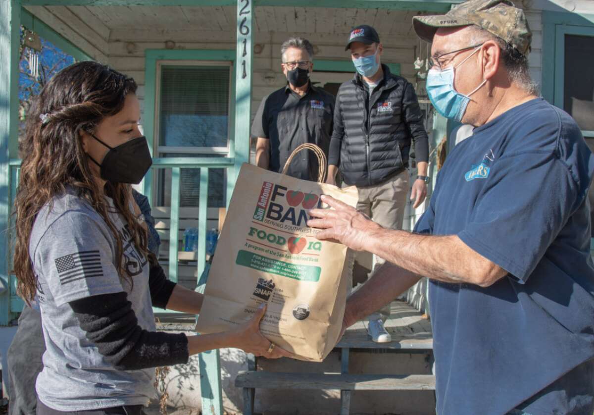 Eva handing food to Frank Campos, a West Side resident who received a delivery on Monday, according to the San Antonio Express-News.