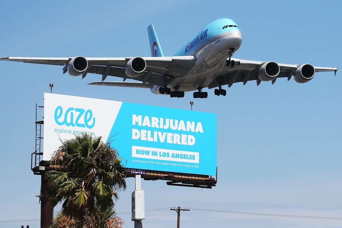 An airplane descends to land at Los Angeles International Airport above a billboard advertising the marijuana delivery service Eaze on July 12, 2018 in Los Angeles, Calif.