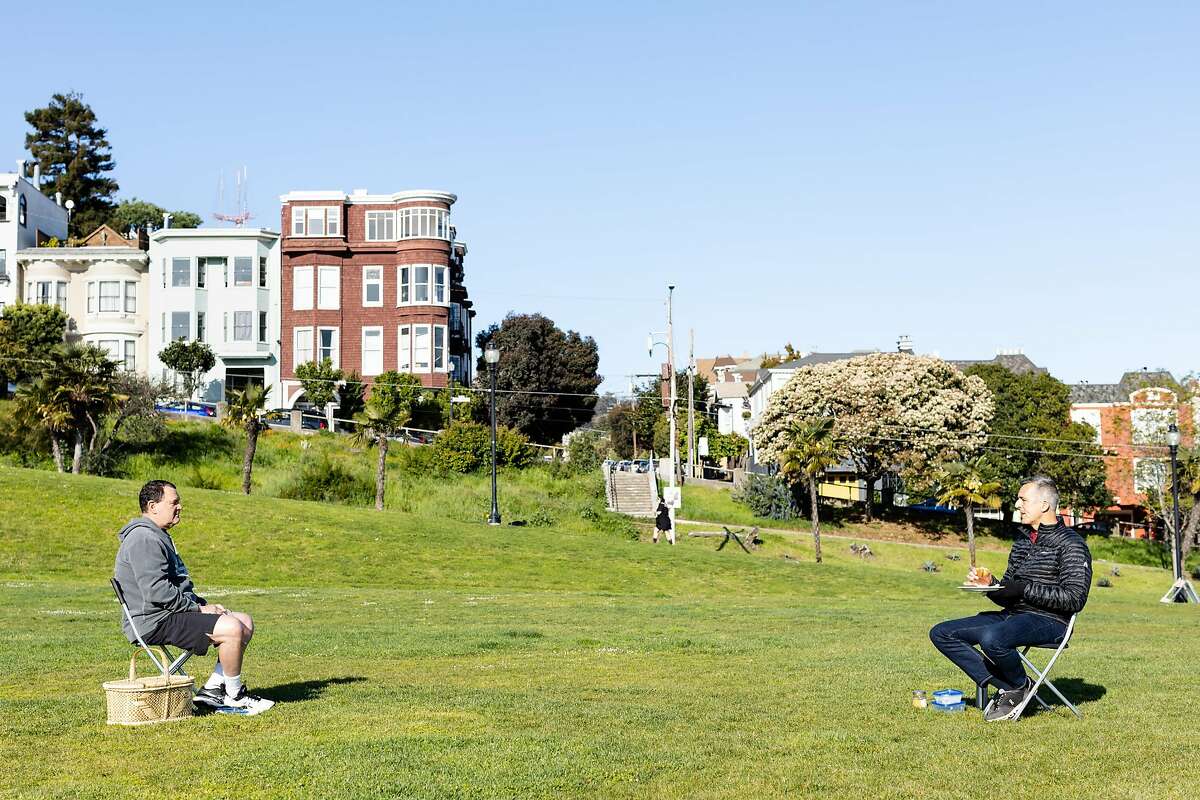 Marius Greenspan (left) and Jim Maloney have breakfast while maintaining social distance at Dolores Park during the shelter-in-place order on April 1, 2020, in San Francisco.