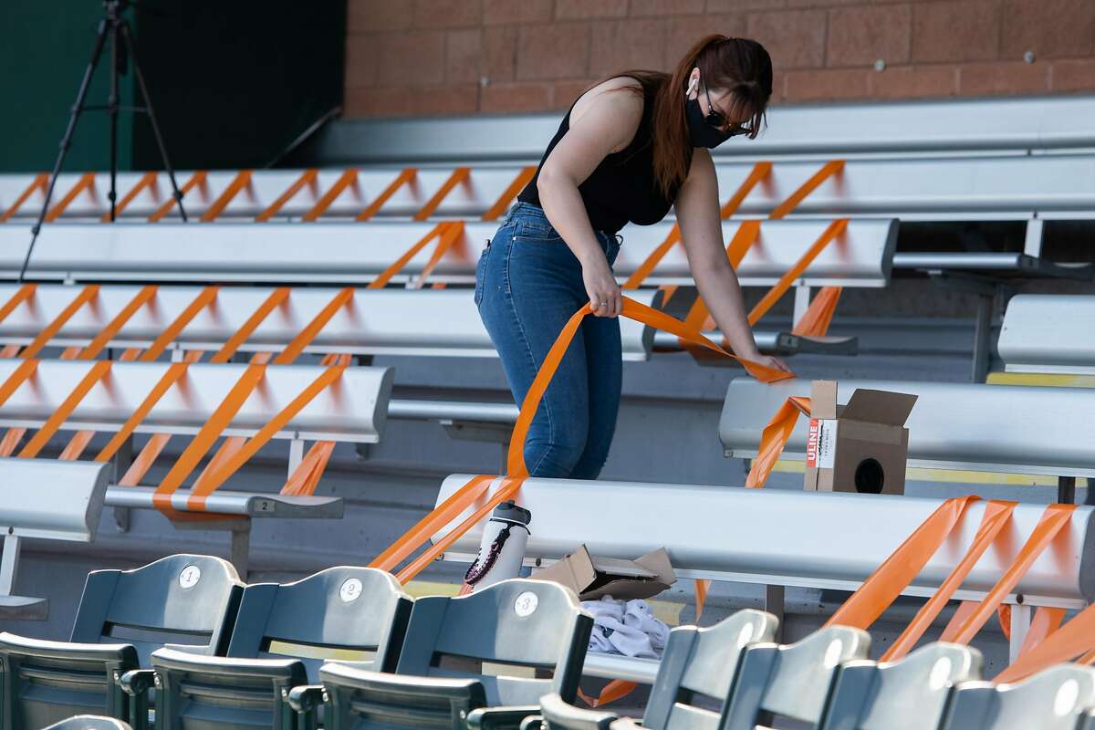 Jacquie Freeman tapes seats to help enforce social distancing among the few fans who will be allowed to attend Giants spring games at Scottsdale Stadium.