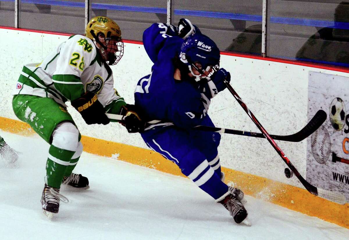 Darien’s Teddy Dyer, right, and Notre Dame-West Haven’s Ryan Ahearn converge on the puck during a game in West Haven in 2019.