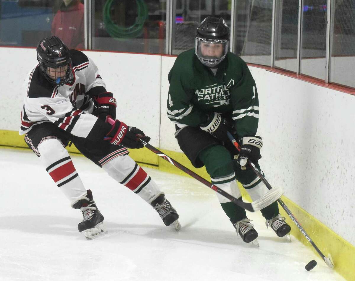 Northwest Catholic’s Connor Melanson (4) controls the puck along the boards while being pressured by New Canaan’s Alex Sotirhos (3) during a game in January.
