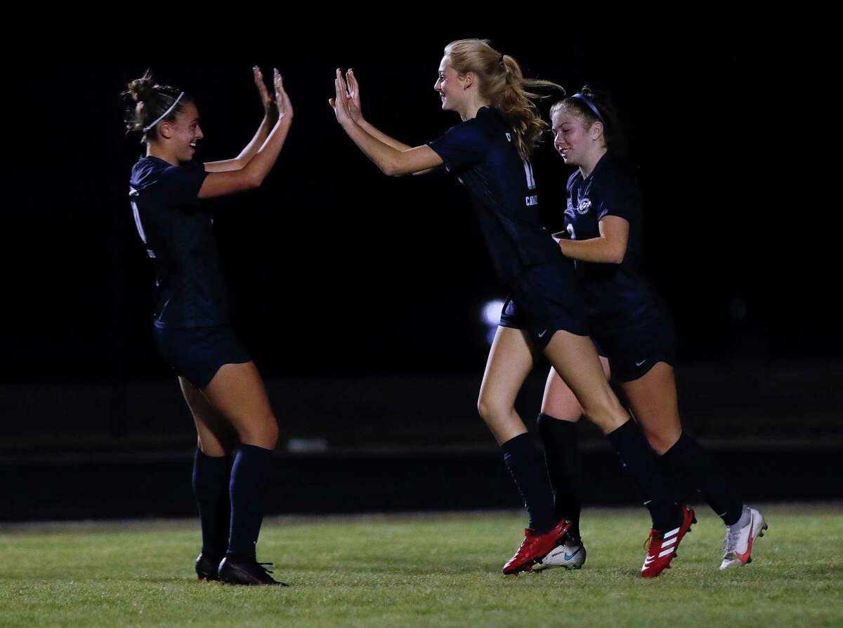 College Park’s Carli Rabson, center, gets a high-five from Taylor Molina (10) after the two connected for a goal in the first period of a District 13-6A high school soccer match at College Park High School, Tuesday, Feb. 23, 2021, in The Woodlands.