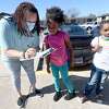 Amber Young gets Nevaeh Wyatt's name listed after she picks up her book and snack with Plymouth Village neighbor Kimora Sears during the Beaumont ISD Parent Involvement Committee's caravan Tuesday. Committee members and BISD staff joined in the event to bring books, snacks and toiletries to area students during this week's virtual learning. Photo made Tuesday, February 23, 2021 Kim Brent/The Enterprise