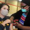 Ezgi Erken, of Trumbull, receives a shot of COVID-19 vaccine from nurse Martine Bristhole at the new vaccination clinic set up in the gymnasium of Central High School, in Bridgeport, Conn. Jan. 20, 2021.