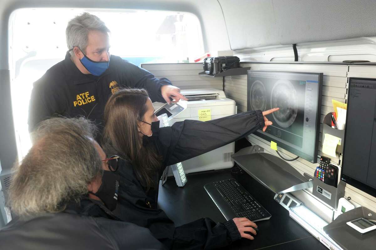Rachel Beninati of the Connecticut State Police forensics lab, seated center, looks at high resolution scans of a bullet casings during a demonstration inside the ATF’s National Integrated Ballistic Information Network (NIBIN) mobile van in Bridgeport, Conn. Feb. 24, 2021. The van will be available to the Bridgeport Police Department for the thirty-day training period. Beninati is seen here with the ATF’s John Hayes, standing, and Bridgeport police detective Paul Nikola.
