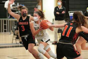 Trumbull's Grace Lesko (23) drives the ball to the basket between Ridgefied's Kelly Chittenden (3), left, and Harley Zins (11) during girls basketball action in Trumbull, Conn., on Wednesday Feb.10, 2021.