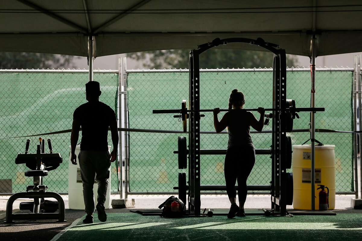 Michelle Espland (right) exercises in the outdoor tent at 24 Hour Fitness in Walnut Creek, California on Wednesday, Dec. 16, 2020.