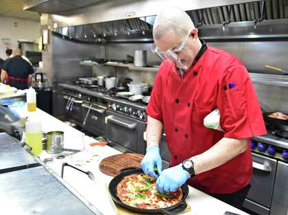 Atillio Marini, chef and owner of the Cast Iron Chef Chop House and Oyster Bar in New Haven puts on the finishing touches of his cast iron pizza creation on Feb. 23, 2021 that will part of his new restaurant venture in Milford.