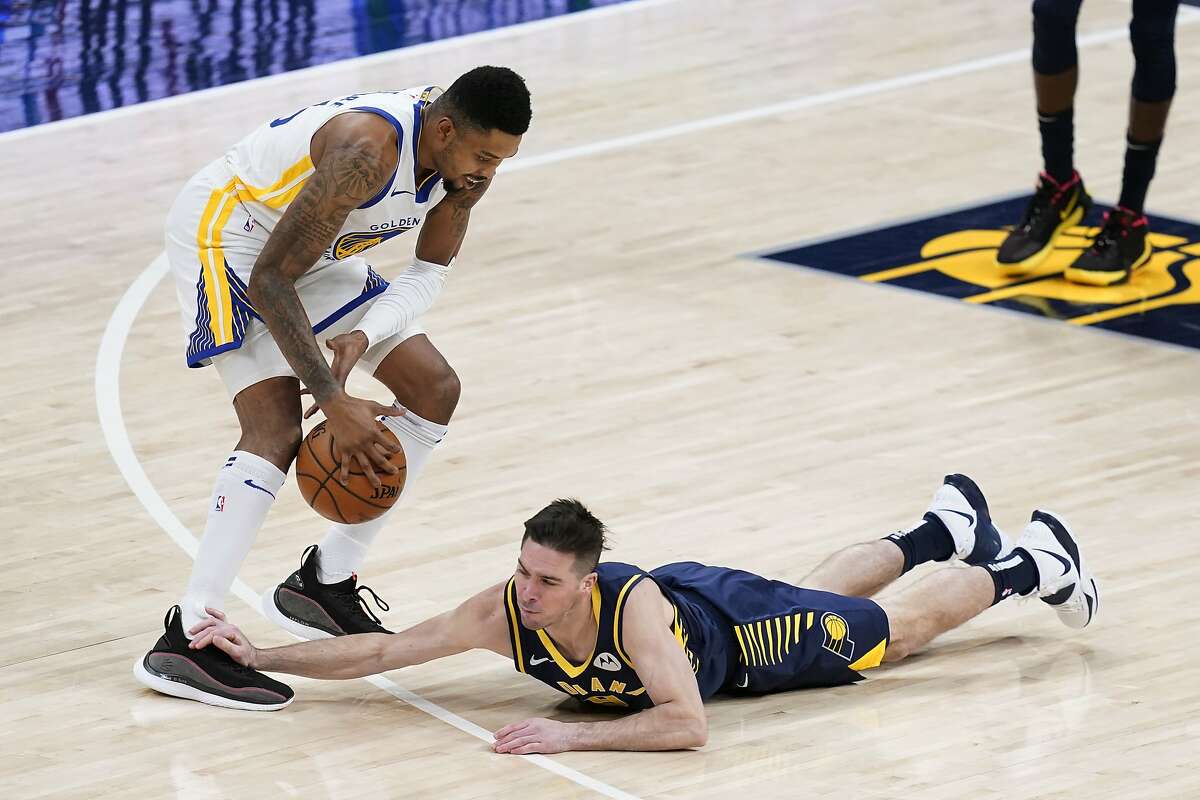 Indiana Pacers' T.J. McConnell (9) dives for a loose ball against Golden State Warriors' Kent Bazemore during the first half of an NBA basketball game Wednesday, Feb. 24, 2021, in Indianapolis. (AP Photo/Darron Cummings)