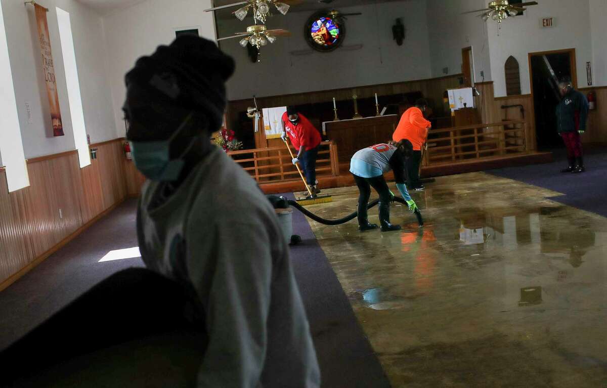 People clean up water from a busted pipe Saturday, Feb. 20, 2021, at Ebenezer United Methodist Church in Houston.
