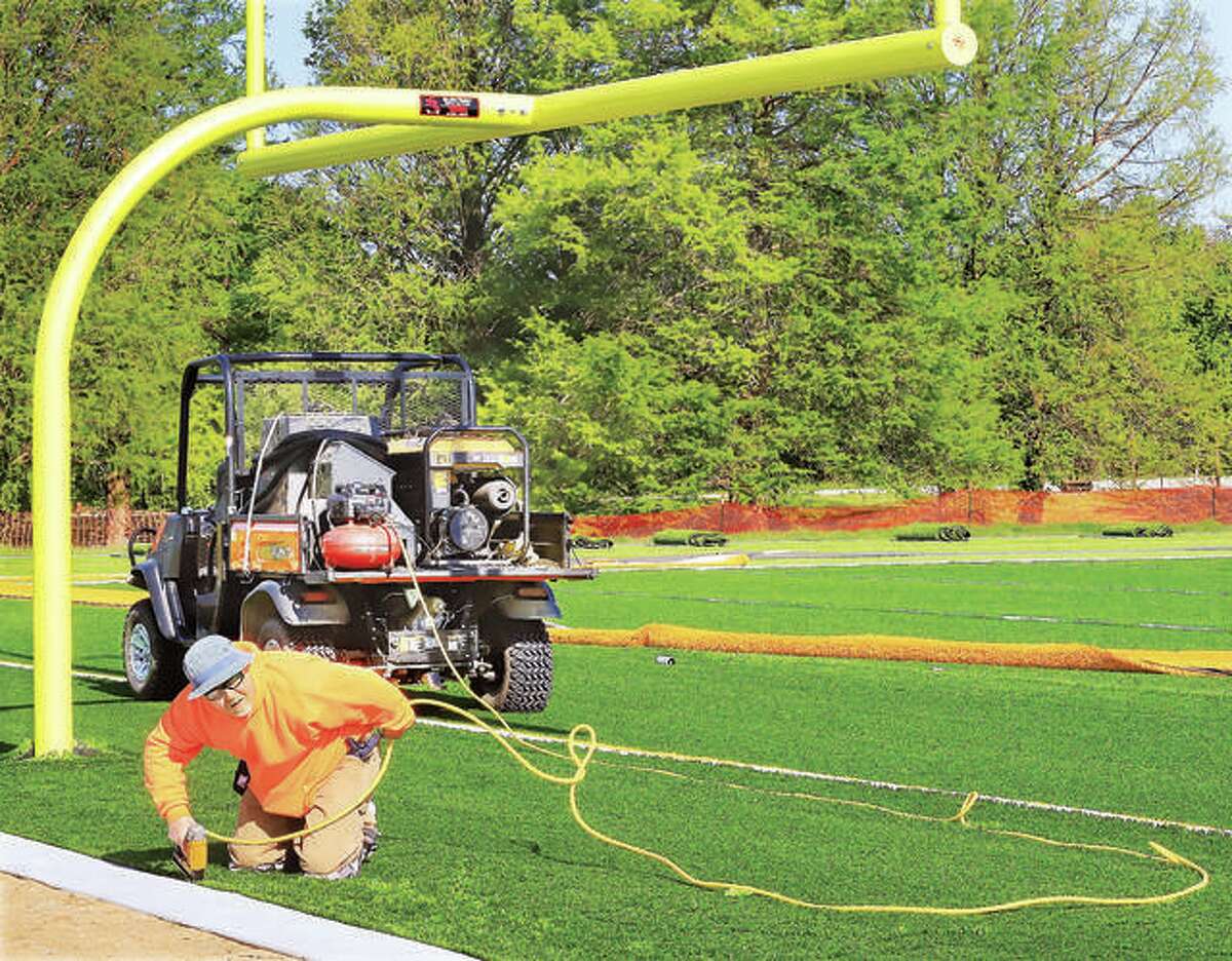 A worker for the company which installed two new artificial turf fields at Alton’s Gordon Moore Park, staples the new turf down on the end of Field 3, a combination football/soccer field. Field 4 is a tournament-size soccer field which is suitable for IHSA sanctioned play.