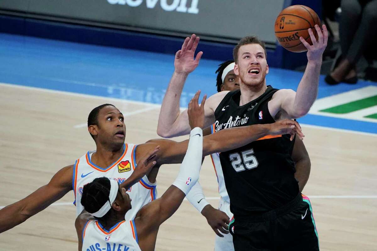 San Antonio Spurs center Jakob Poeltl (25) reaches for a rebound in front of Oklahoma City Thunder center Al Horford, left, and guard Shai Gilgeous-Alexander, bottom, during the first half of an NBA basketball game Wednesday, Feb. 24, 2021, in Oklahoma City. (AP Photo/Sue Ogrocki)