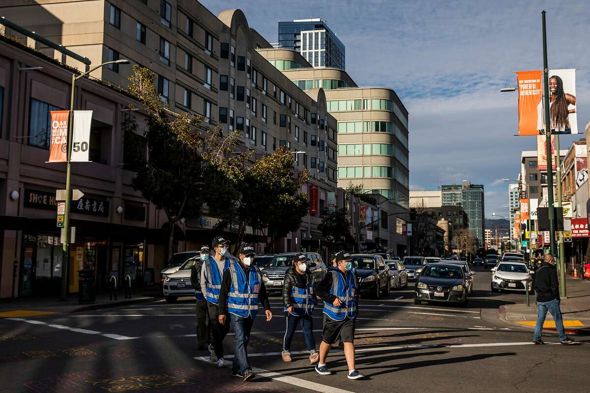 Volunteer safety patrol members in blue vests walk in groups in Oakland Chinatown Feb. 16, 2021. Community members are on heightened alert after the recent increase in violent crimes, many caught on camera, toward the Asian American community throughout the Bay Area. 