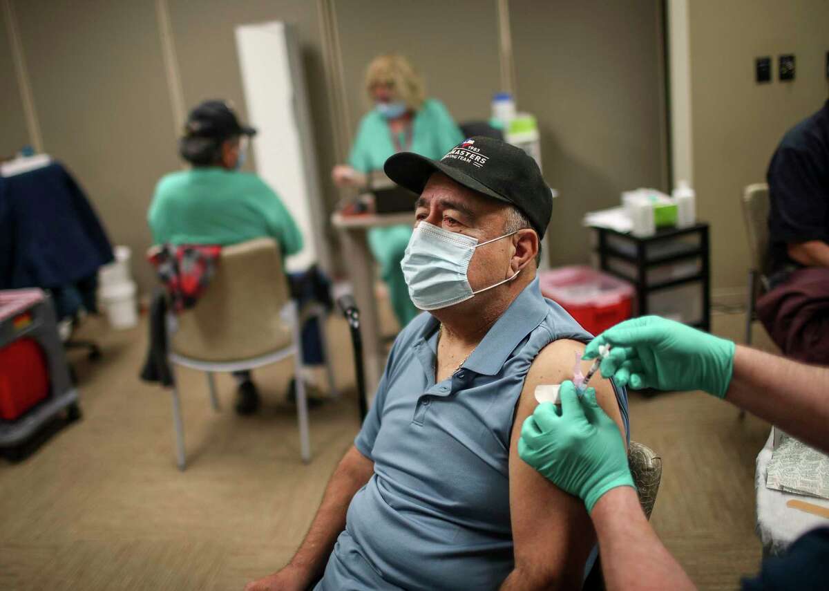 Manuel Gaitan, a Vietnam veteran, gets a vaccine shot from Michael Clark, a nurse, on Feb. 20, 2021, at Michael E. DeBakey VA Medical Center in Houston.