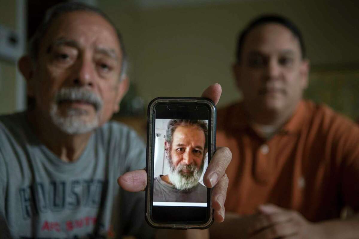 Isaac and Lawrence Ibarra show a picture Isaac's brother, Gilbert Rivera, on a phone Wednesday, Feb. 24, 2021 in Houston. Rivera died of hypothermia after his apartment lost power amid bitter cold temperatures during the week of Feb. 14, 2021.