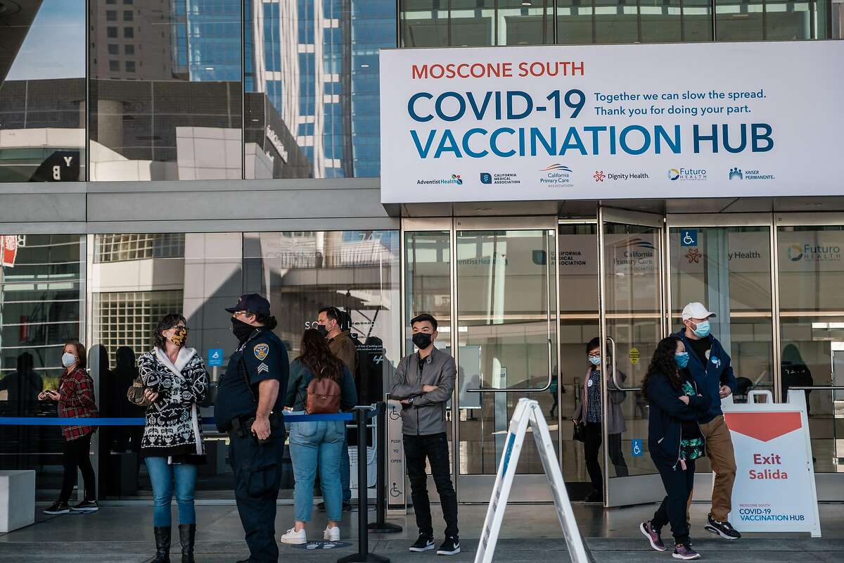 People are seen waiting on line to enter the mass vaccination site at the Moscone Center in San Francisco. The CDC warns of national rise in virus cases, but Bay Area is still dropping and counties are reopening.