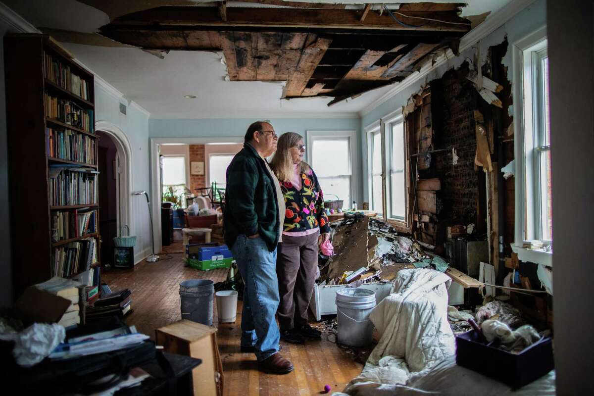 Judie and Martin Beller are standing in Houston on Thursday, February 25, 2021 in the middle of their destroyed living room.  The couple tried to stay as warm as possible as temperatures plummeted into teens during winter storm Uri.  They turned on their gas fireplace, which they hadn't used, and soon their house was taken over by the fire.