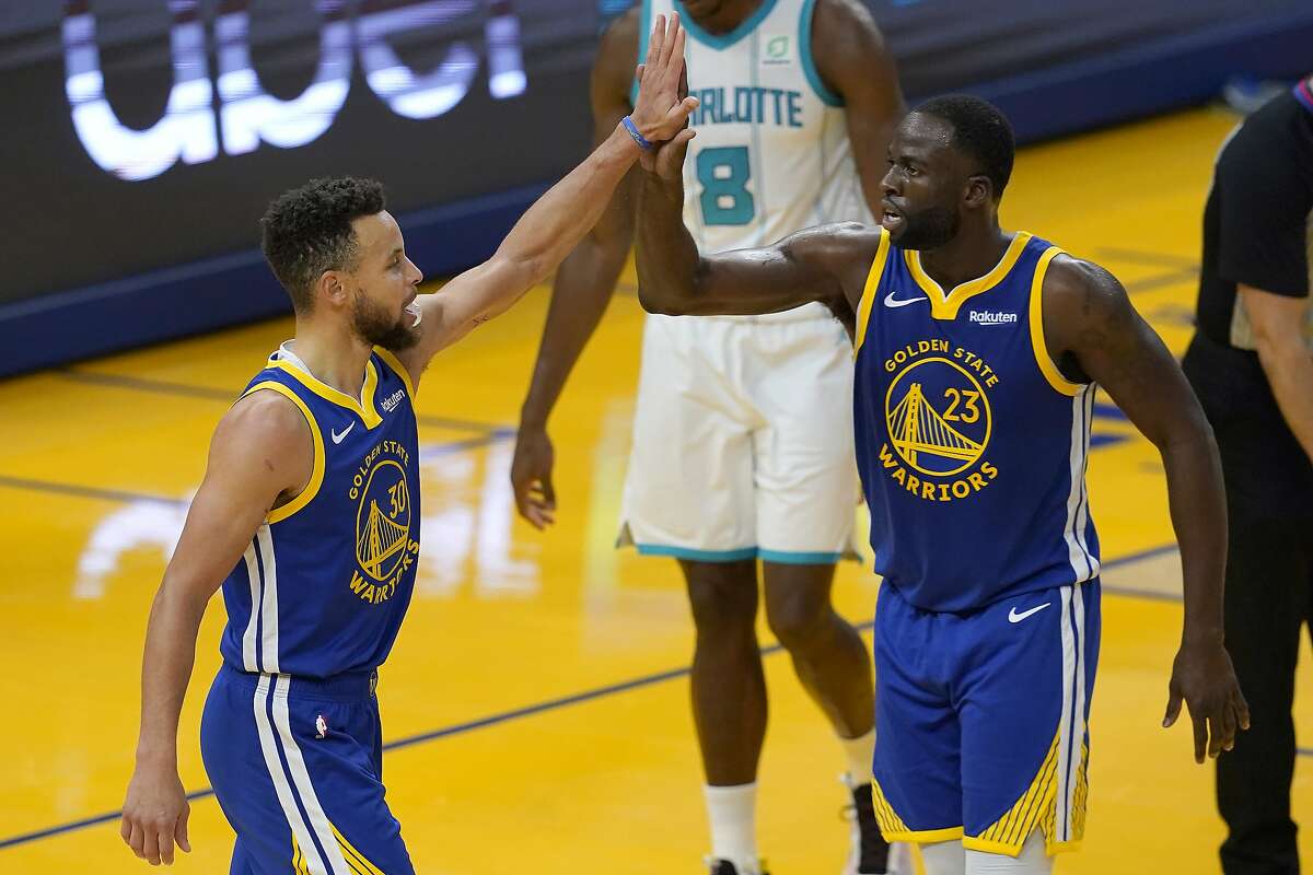 Golden State Warriors guard Stephen Curry, left, celebrates with forward Draymond Green (23) during the first half of an NBA basketball game against the Charlotte Hornets in San Francisco, Friday, Feb. 26, 2021. (AP Photo/Jeff Chiu)