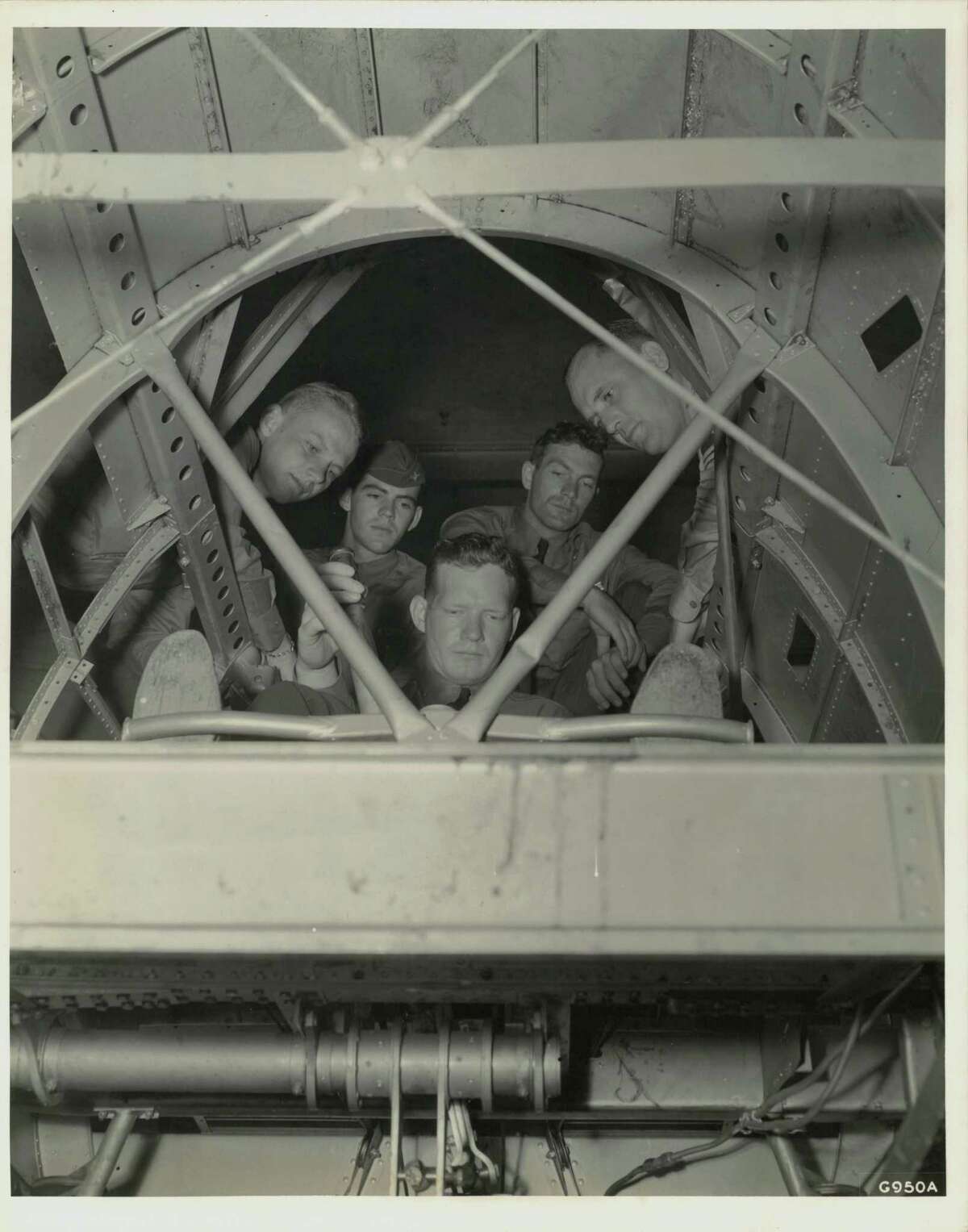 From the bomb bay looking up -- Inside a full scale cutaway model of a giant twin motored plane, used at Randolph Field, Texas, for ground instruction, a group of Flying Cadets experiment with the controls. Uncle Sam is going to train 7,000 pilots annually for his Air Corps and 3,600 bombardiers and navigators. A good idea of the intricate construction of a modern fighting plane can be obtained here. (Texas)