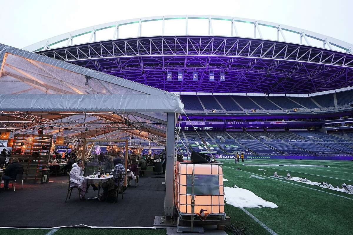 People eat dinner in an outdoor dining tent set up at Lumen Field, the home of the Seattle Seahawks NFL football team, Thursday, Feb. 18, 2021, in Seattle. The "Field To Table" event was the first night of several weeks of dates that offer four-course meals cooked by local chefs and served on the field at tables socially distanced as a precaution against the COVID-19 pandemic, which has severely limited options for dining out at restaurants in the area. (AP Photo/Ted S. Warren)