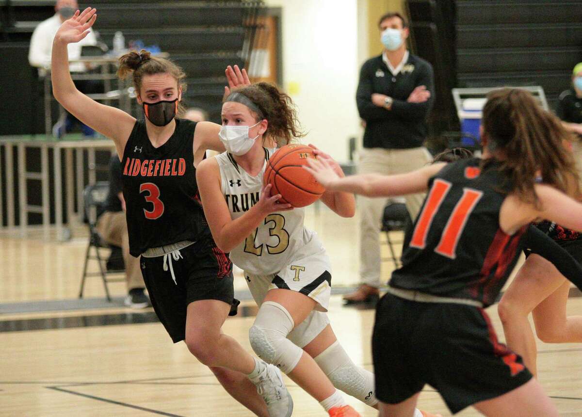 Trumbull's Grace Lesko (23) drives the ball to the basket between Ridgefied's Kelly Chittenden (3), left, and Harley Zins (11) during girls basketball action in Trumbull, Conn., on Wednesday Feb.10, 2021.